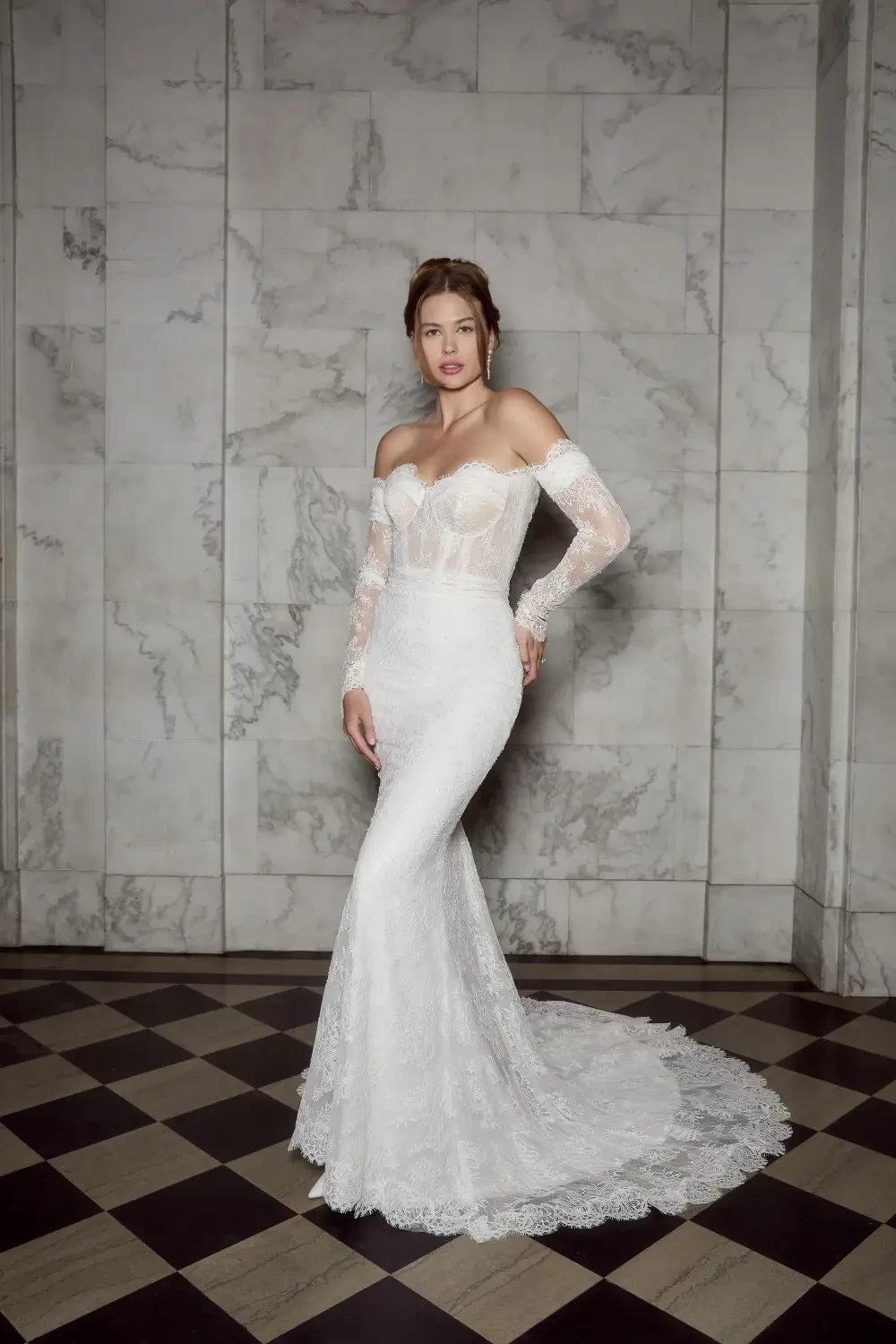 model is wearing an off the shoulder long sleeve wedding gown