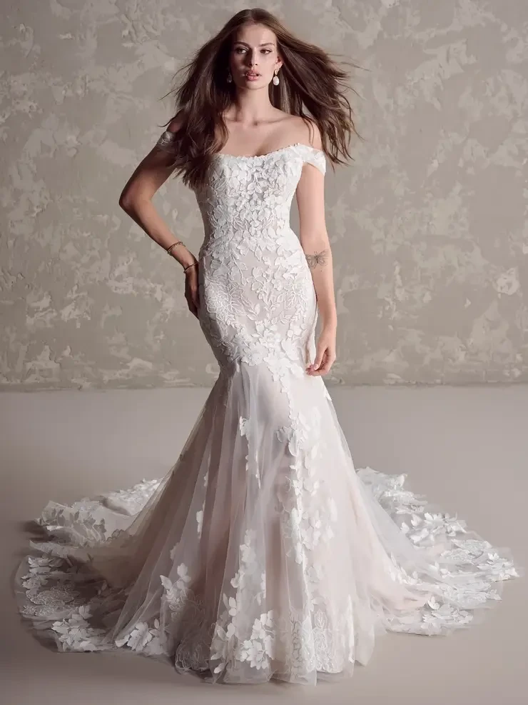 A woman wearing an elegant off-the-shoulder wedding dress with intricate lace detailing and a flowing train.